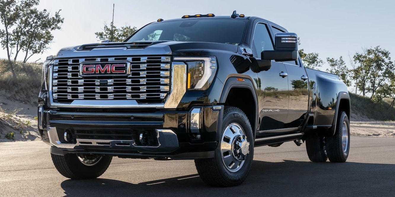 A black GMC Sierra HD pickup truck on a winding the road near some plains.