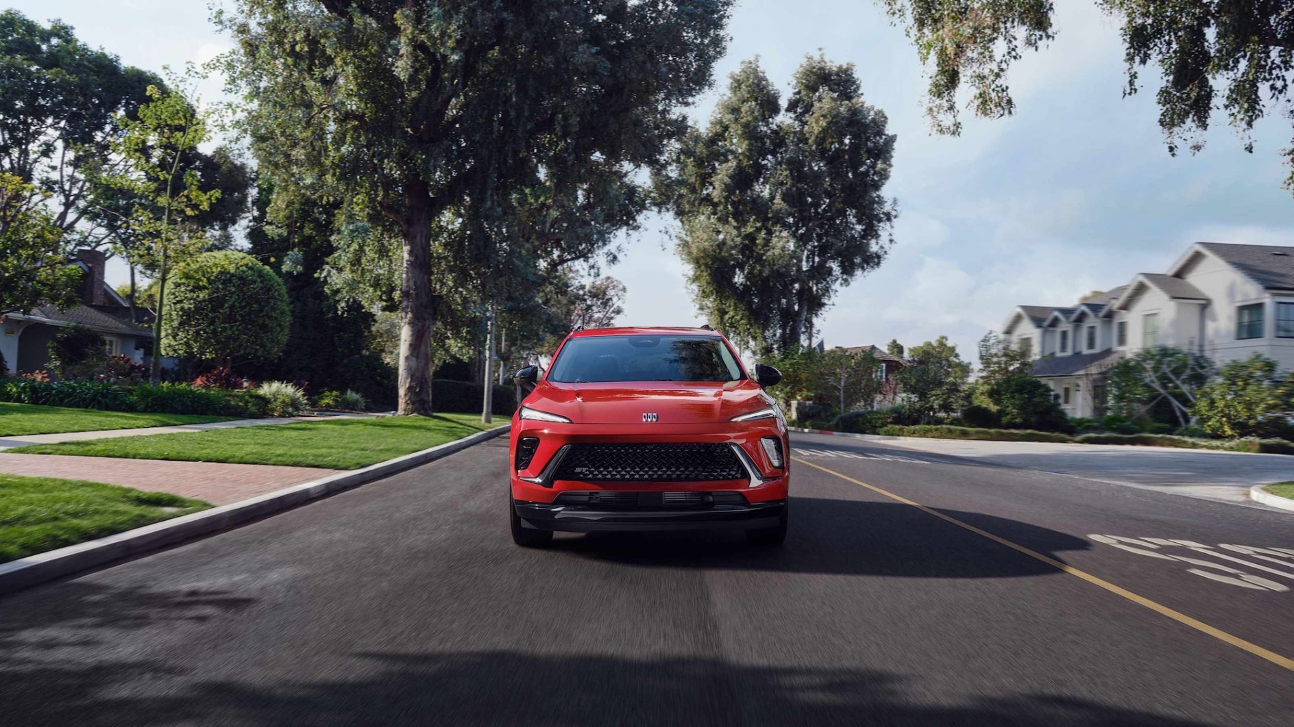 A front view of a red Buick Envision driving down the road.