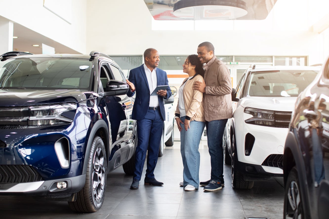 A car salesman selling a vehicle to a couple.