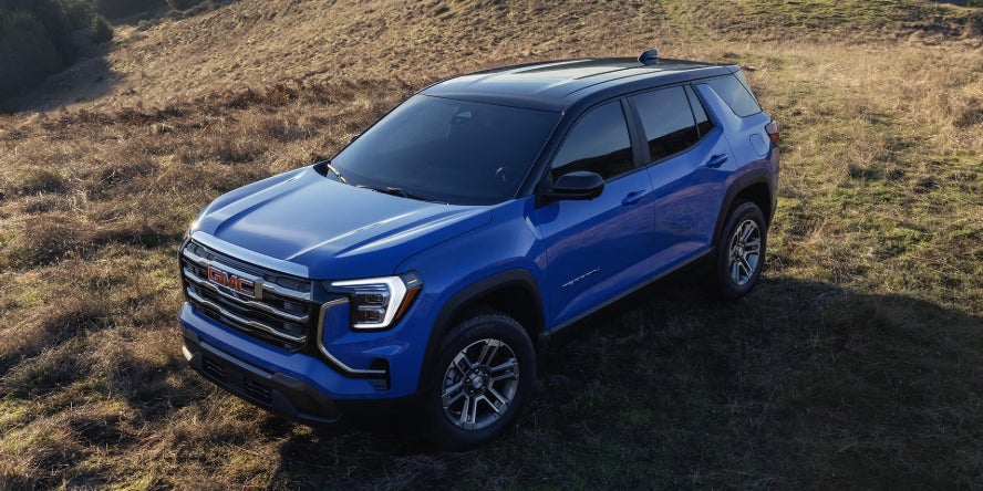 A blue GMC Terrain parked in a field.